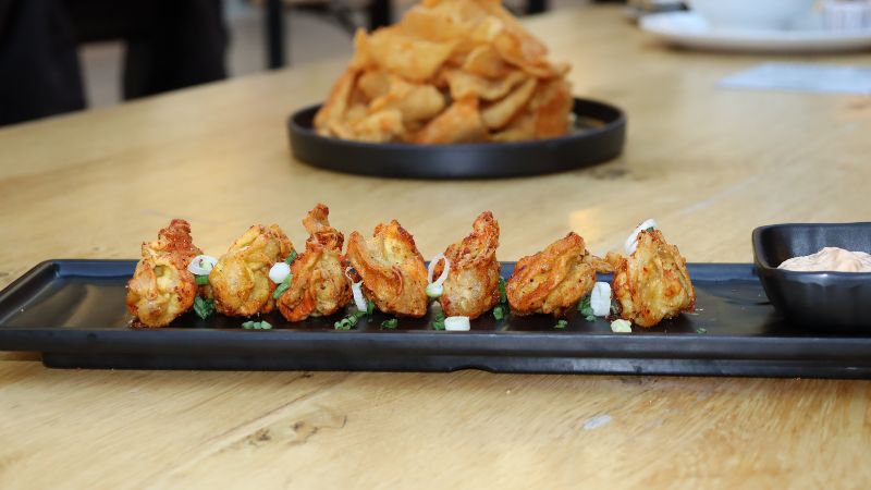 A plate of friend wontons with seasoning.